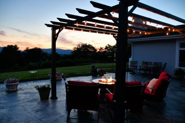Comfortable outside seating area with fire pit table and pergola with lights in evening or morning
